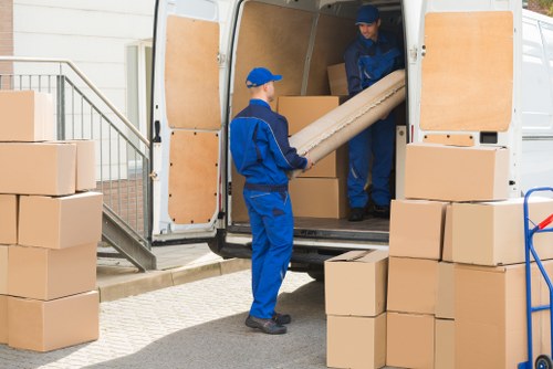 Piano movers carefully handling an upright piano in a Finsbury Park home